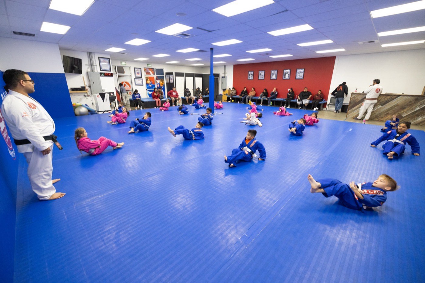 Parents watch from benches while kids drill on the mat