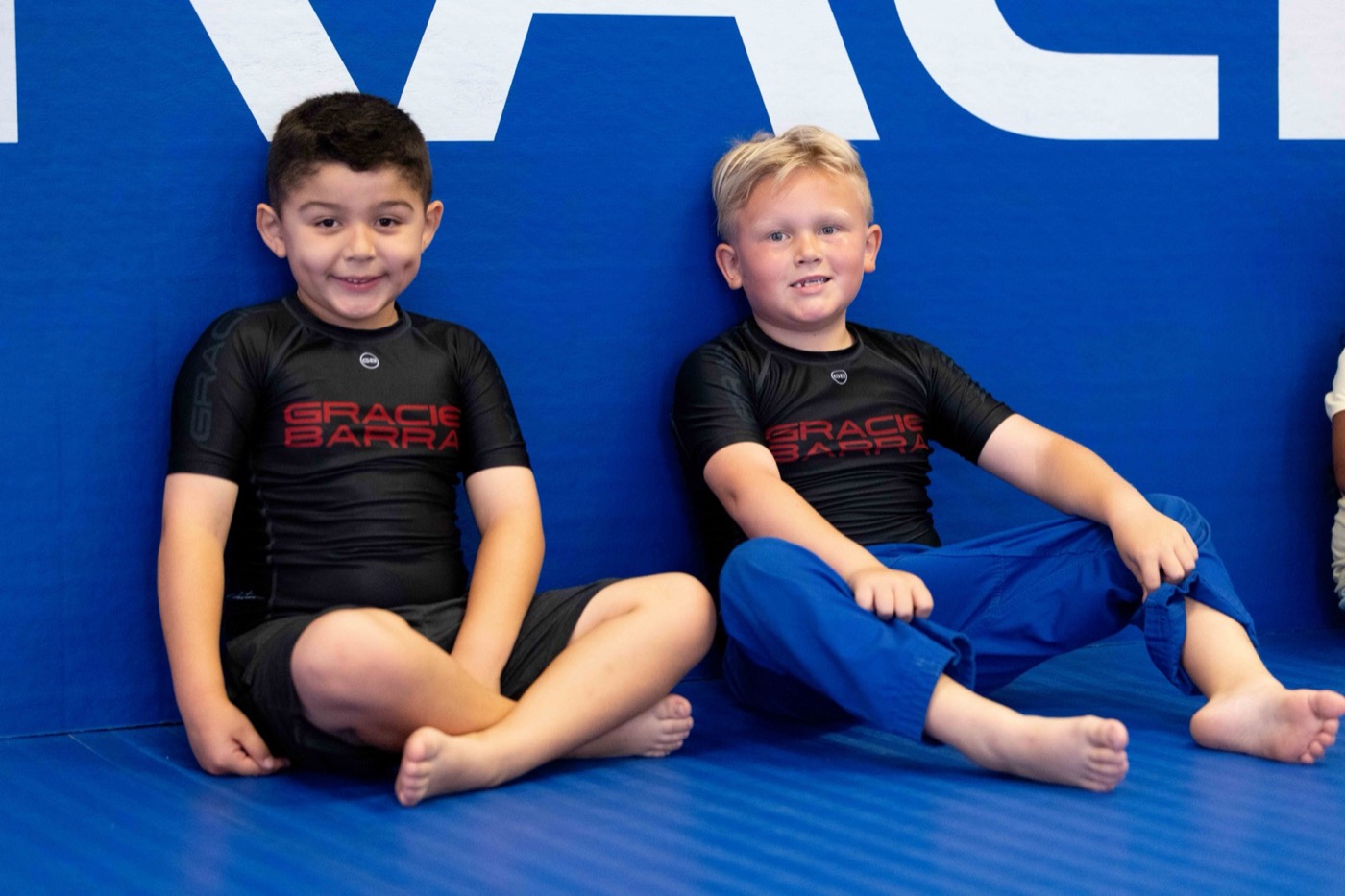 Two young students grin at the camera against the blue wall